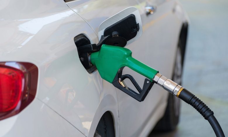 Surtidor de gasolina con boquilla verde repostando combustible a un vehículo.